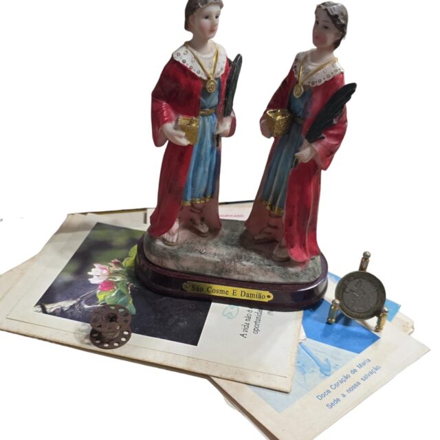 Imagem sacra de resina com diversos papéis antigos e carretel de linha